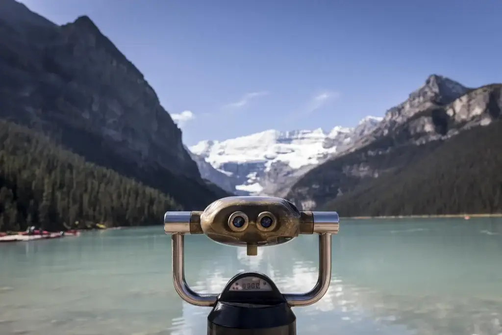 Viewfinder overlooking a serene lake surrounded by majestic mountains and glaciers, ideal for nature photography and sightseeing. The clear blue sky complements the tranquil water, enhancing the picturesque landscape.